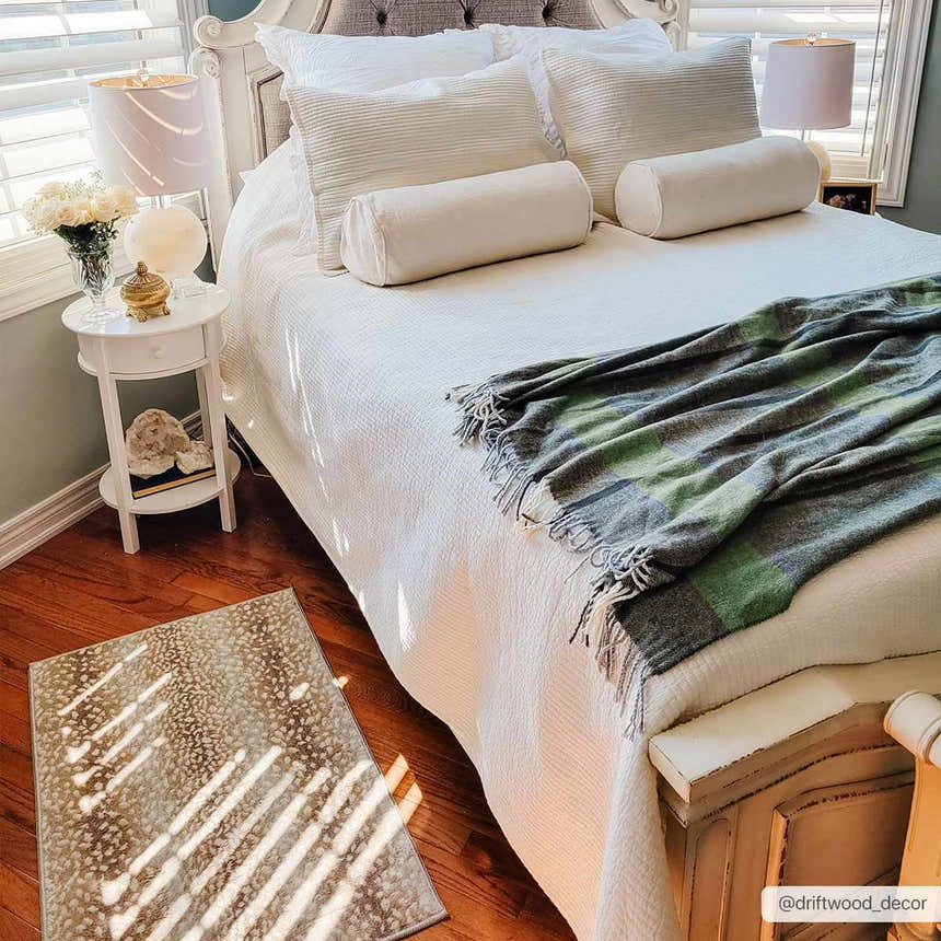 Bedroom scene with Pointblank Tan Leopard Print Rug on hardwood floor, near a white bed and nightstand. Roomscene-Rectangle