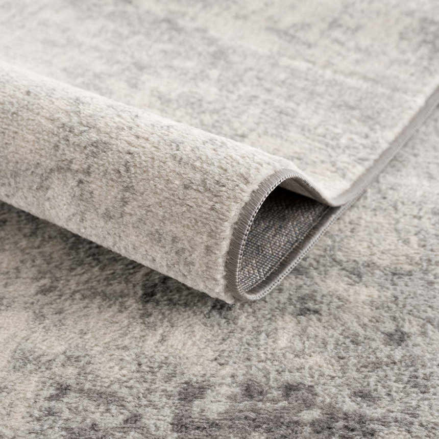 Close-up of the Kalanganan Abstract Gray Rug showing its charcoal, gray, and off-white abstract pattern and soft texture. Fold