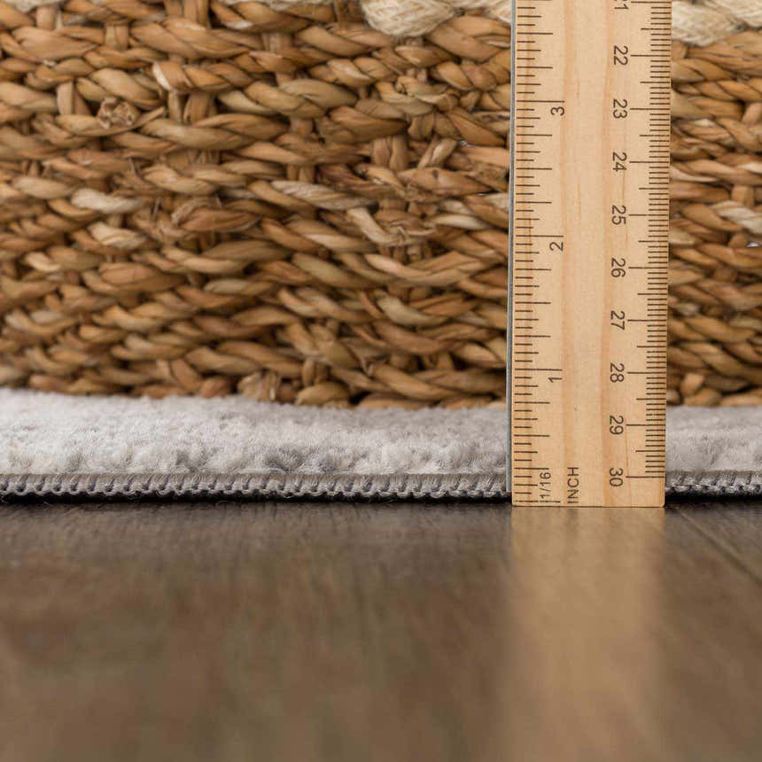 Close-up of the Kalanganan Abstract Gray Rug showing rug thickness with a ruler and woven basket for texture comparison. Pile