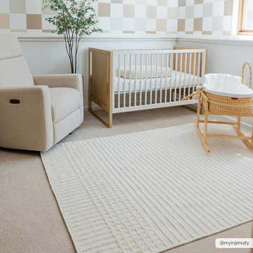 Neutral nursery with Bone Rhun Washable Area Rug, white crib, beige rocker, and checkered accent wall. Roomscene-Rectangle
