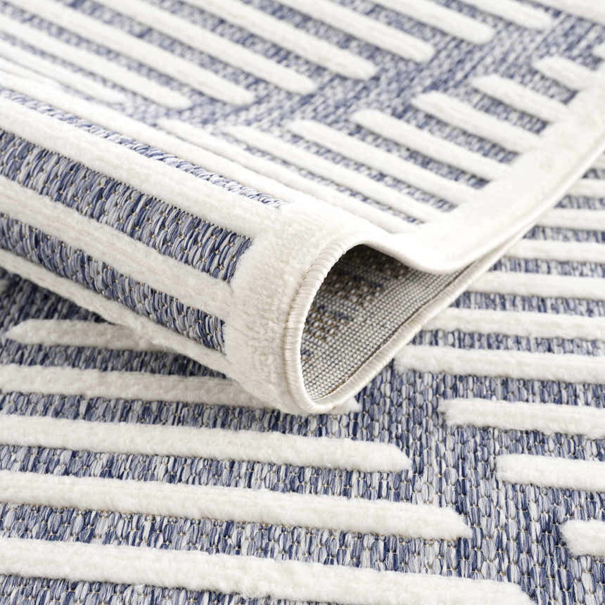 Close up of the Anah Blue Outdoor Rug featuring a contemporary geometric design and textured weave. Fold