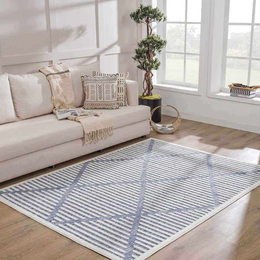 Living room scene with a beige couch and the Anah Blue Outdoor Rug featuring a geometric striped pattern. Roomscene-Rectangle