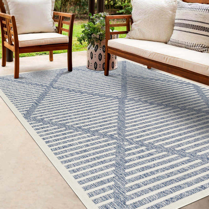 Outdoor patio scene with wood furniture and the Anah Blue Outdoor Rug with geometric stripes. Roomscene-Rectangle