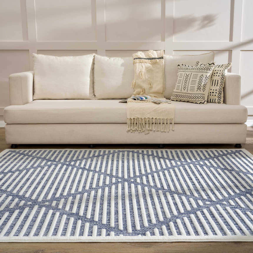 Living room scene with a beige sofa and the blue and white geometric Anah Blue Outdoor Rug. Roomscene-Rectangle