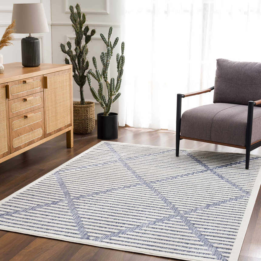 Living room scene with a gray chair and the Anah Blue Outdoor Rug featuring a geometric pattern. Roomscene-Rectangle