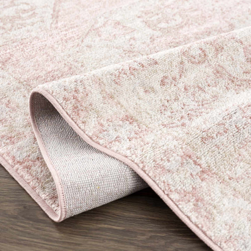 Close-up of the Snead Pink Floral Rug showing its light beige and pale pink floral pattern and machine-woven texture. Fold