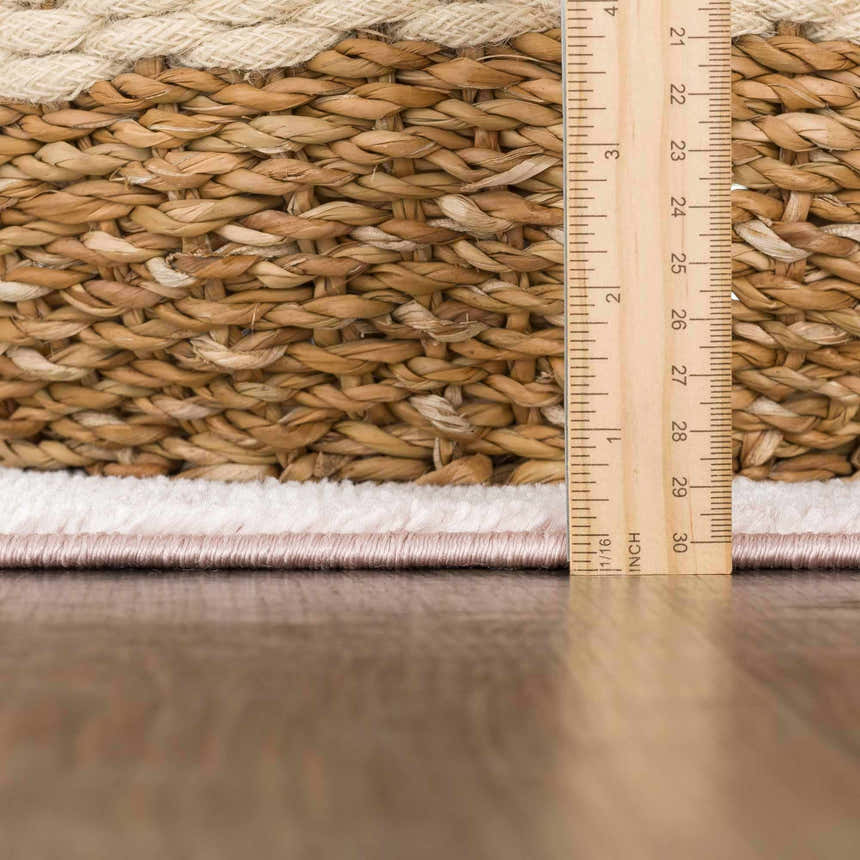 Close-up of the Snead Pink Floral Rug showing the rug's pile height with a ruler and the light beige and pale pink colors. Pile