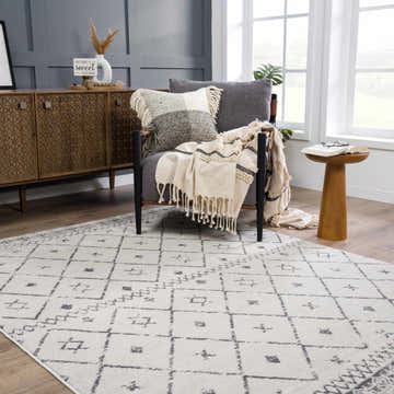Living room scene with a gray chair and the geometric Tigris Area Rug in charcoal, gray, and white. Roomscene-Rectangle