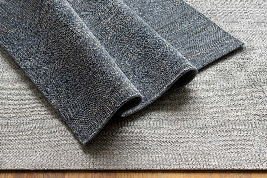 Close-up of the hand-knotted Hoole Area Rug. Features dark blue, denim, and off-white wool textures. Contemporary style. Styleshot
