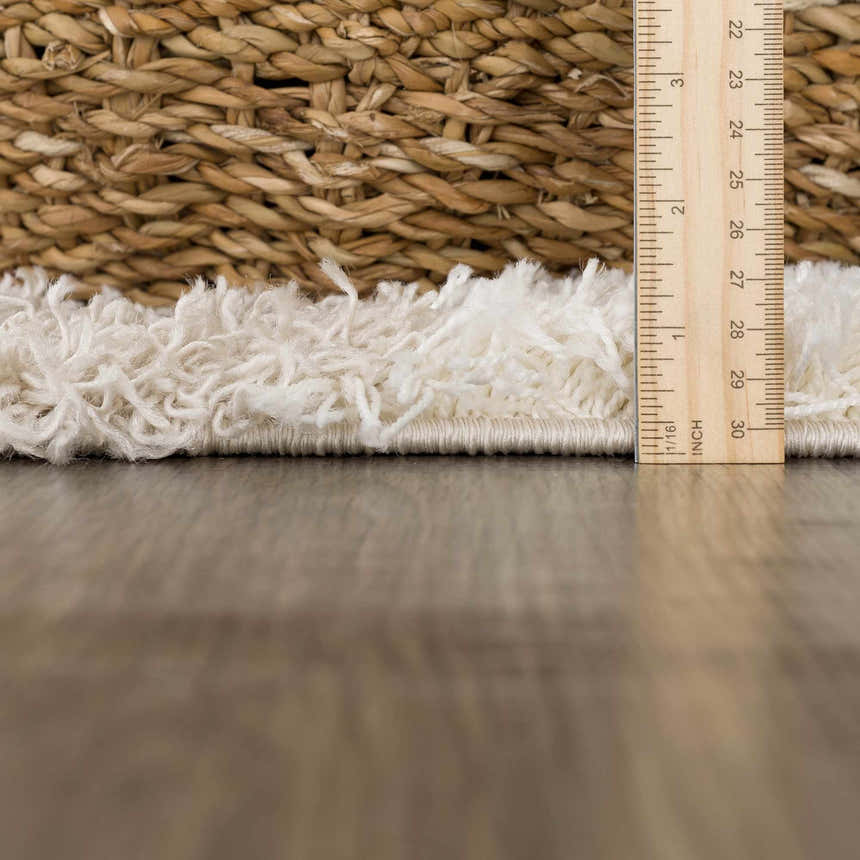 Close-up of the Atira Light Brown Checkered Area Rug showing the shag texture and pile height with a ruler. Pile
