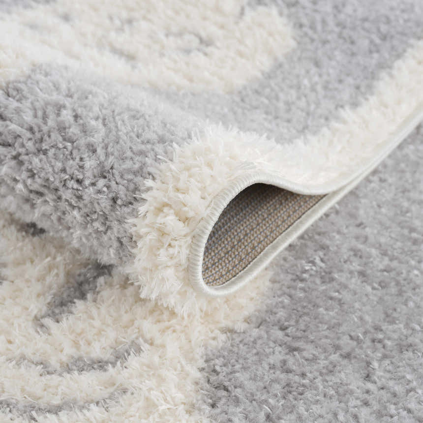 Close-up of the Zane Gray Tibetan Tiger Area Rug showing its cream and light gray shag texture and woven backing. Fold