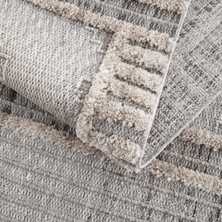 Close-up of the Amaga High-Low Rustic Rug showing its cream and gray geometric pattern and high-low textured design. Fold