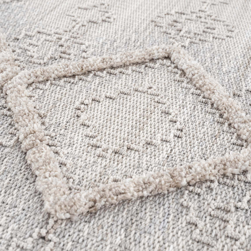 Close up of the Amaga High-Low Rustic Rug. Cream, light beige, and gray geometric pattern with high-low texture. Texture