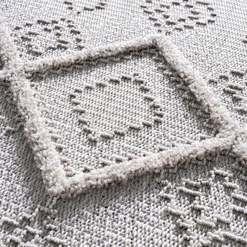 Close-up of the Amaga High-Low Rustic Rug showcasing its geometric pattern and high-low texture in charcoal and cream. Texture