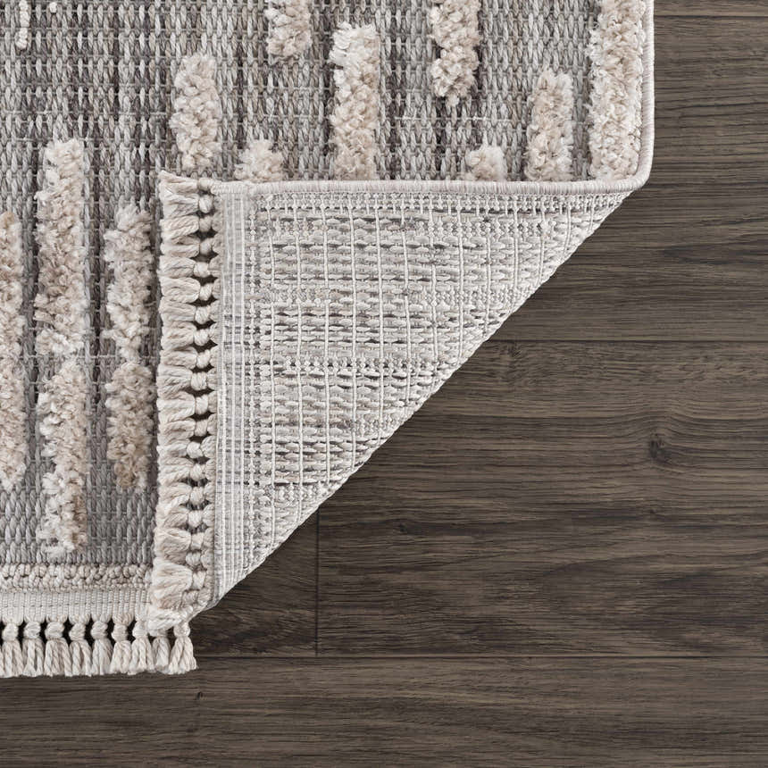Close-up of the Poydras High-Low Rustic Rug showing charcoal, gray, and light beige tones and high-low pile texture. Fold