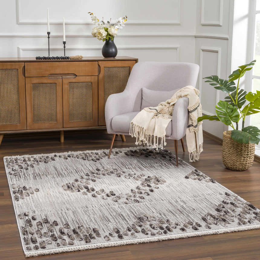 Living room scene with a charcoal and cream Cabarroguis Area Rug, light gray armchair, and wooden cabinet. Roomscene-Rectangle