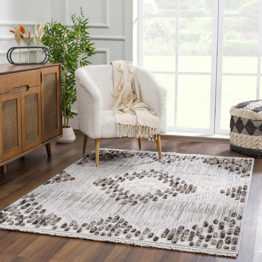 Living room scene with a cream chair and charcoal Cabarroguis Area Rug with geometric pattern on dark wood floor. Roomscene-Rectangle