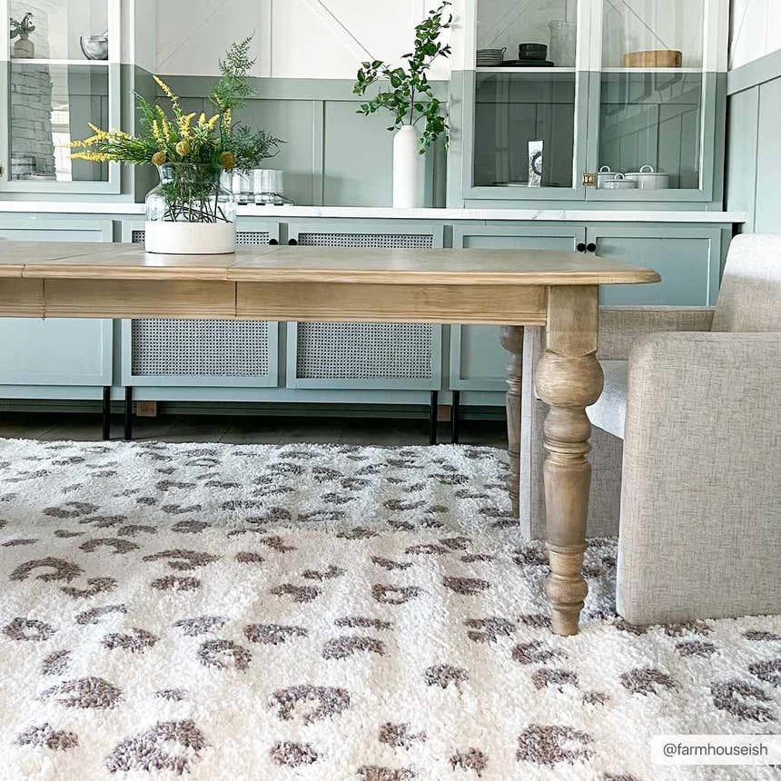Dining room with a Zhen Pink Spots Leopard Rug, light wood table, and pale green cabinets. Roomscene-Rectangle
