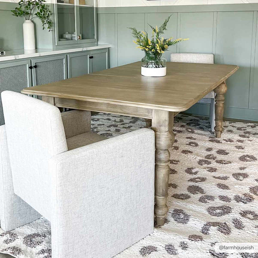 Dining room scene with a Zhen Pink Spots Leopard Rug, wooden table, and light gray chairs. Roomscene-Rectangle