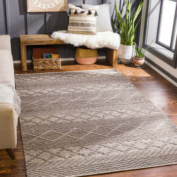 Living room scene with Abuyon Jute Carpet in charcoal and light beige. Bohemian rug styled with a sofa, bench, and plants. Roomscene-Rectangle
