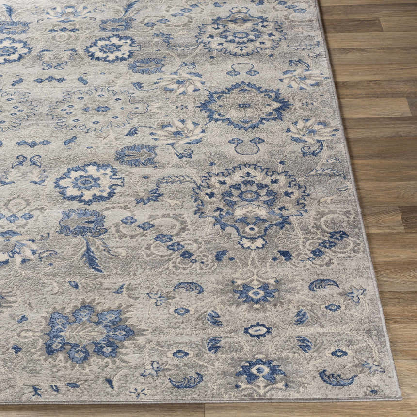 Close-up of the Adairsville Blue Floral Area Carpet, featuring a denim, gray, and ivory traditional floral pattern. Front