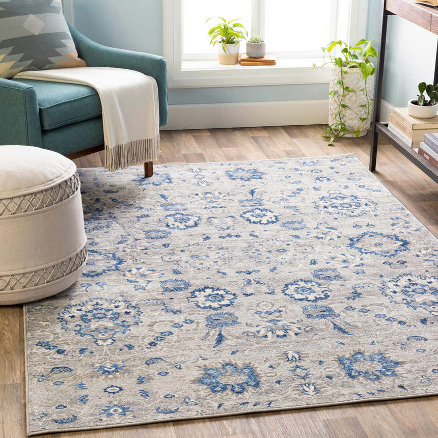 Living room scene with Adairsville Blue Floral Area Carpet, teal chair, ottoman, and natural light. Roomscene-Rectangle