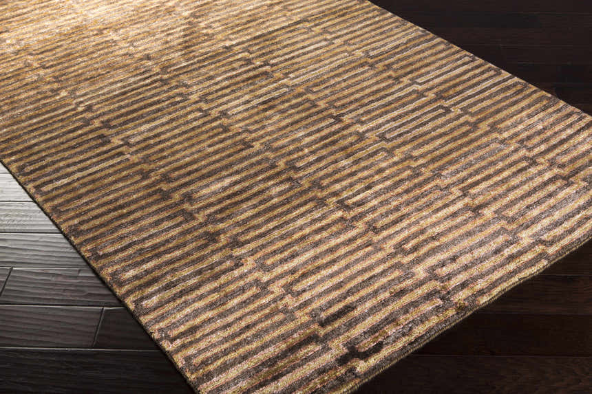 Close-up of the Addieville Area Carpet. Black, brick red, and brown hand-knotted viscose rug with a contemporary geometric pattern. Corner