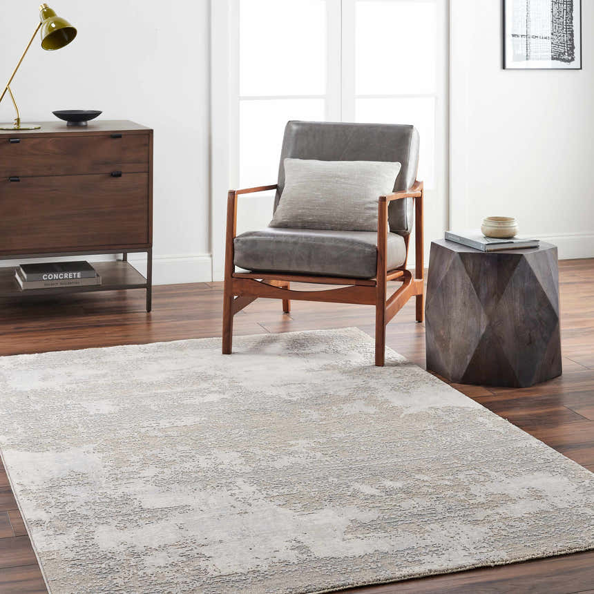 Living room scene with a gray Adwoa Boutique Rug, leather chair, wood side table, and dresser on dark wood floors. Roomscene-Rectangle