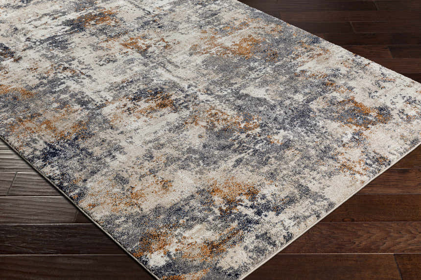 Close-up of the Agpangi Thick Luxe Rug. Abstract design with blue, cream, gray, and dusty coral colors on dark wood floor. Corner