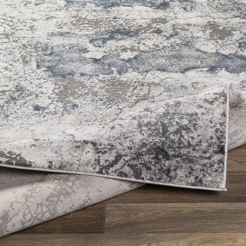 Close-up of the Ainslie Gray Marble Rug showing its charcoal, dark blue, and white contemporary pattern and machine woven texture. Fold