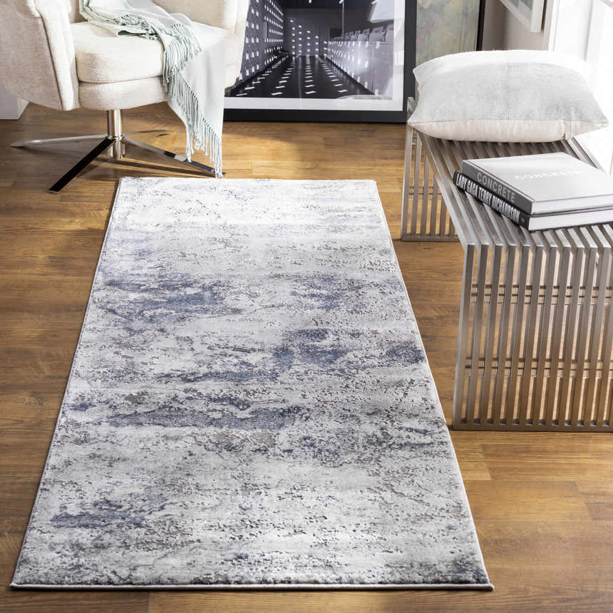 Living room scene with a gray and blue Ainslie Gray Marble Rug, modern chair, and metal bench. Roomscene-Runner