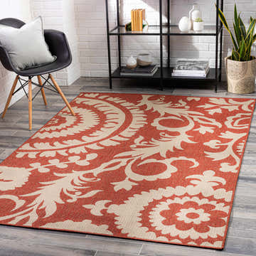 Coastal room scene with Alburnett Burnt Orange Floral Rug, black chair, white brick wall, and modern shelving. Roomscene-Rectangle