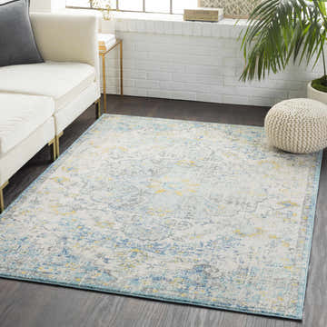 Living room scene with a white sofa and the Aleknagik Area Rug, a vintage style rug in charcoal, beige, gray, mustard, peach, and teal. Roomscene-Rectangle