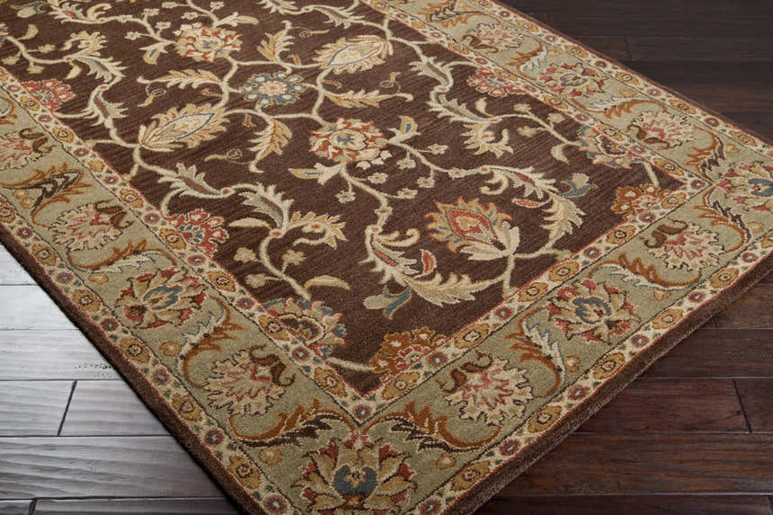 Close-up of the Alexander Brown Regency Wool Carpet. Features a brown floral pattern and olive border on dark wood floors. Corner
