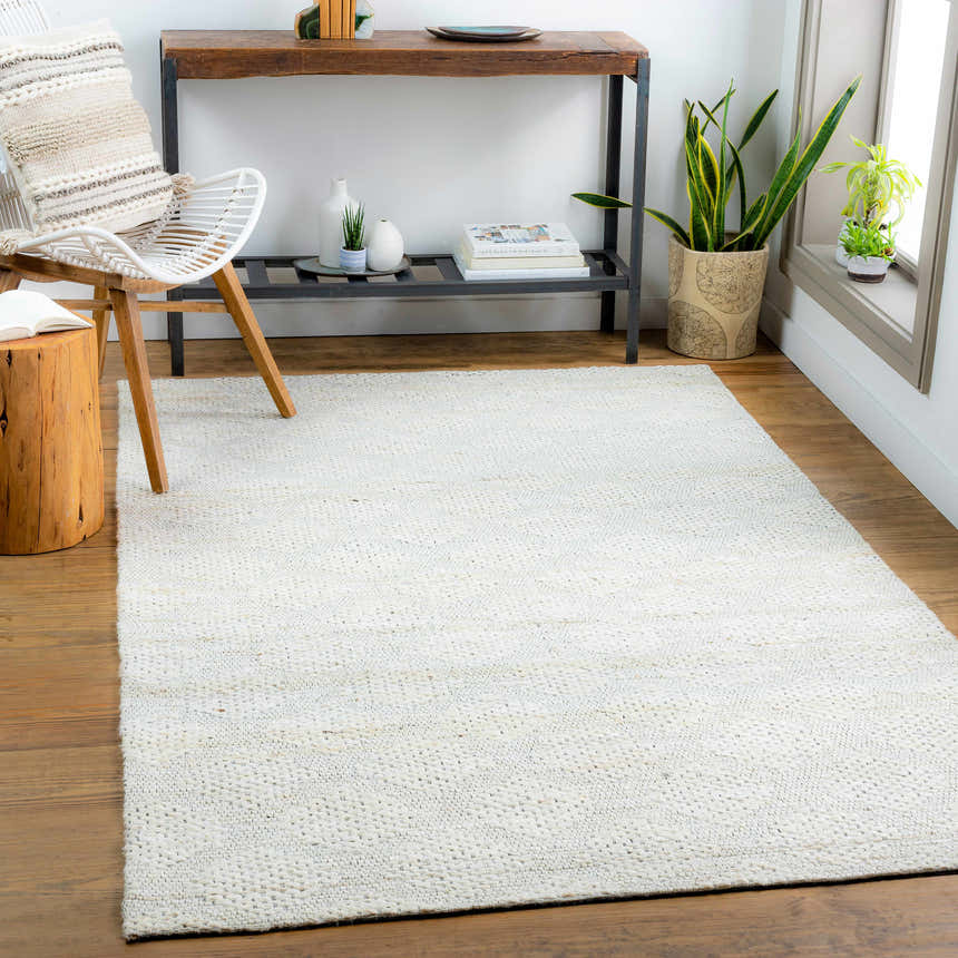 Light and airy living room with a beige Angaston hand-woven jute rug, wood floors, white chair, and console table. Roomscene-Rectangle