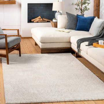 Living room scene with a light beige Annalong Modern High Pile Luxe Rug, cream sofa, gray chair, and fireplace. Roomscene-Rectangle