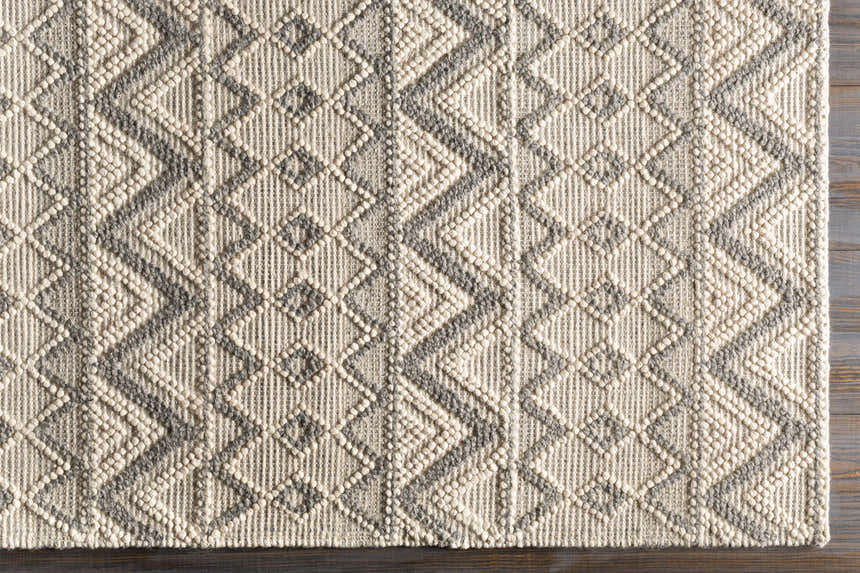 Close-up of the hand woven Whittington Gray&Cream Wool Rug. Features a geometric diamond pattern and textured wool. Swatch