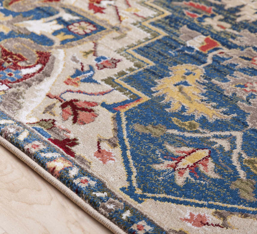Close-up of the Argyle Area Rug, a machine-woven traditional rug with blue, red, yellow, and tan floral patterns. Texture