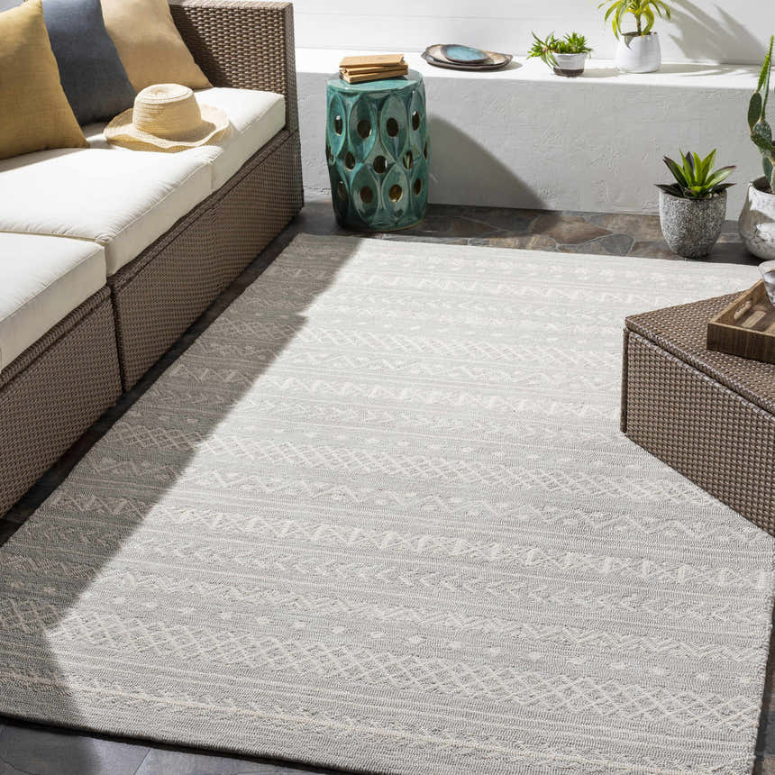 Outdoor patio scene with a cream and light gray Argenton Area Rug, wicker furniture, and potted plants. Roomscene-Rectangle