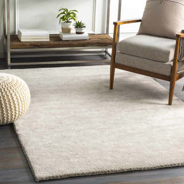 Living room scene with light gray Arkadelphia carpet, wood chair, and woven ottoman. Roomscene-Rectangle