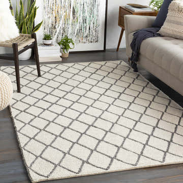 Living room scene with charcoal and cream Arlesey Carpet, sofa, chair, plants, and modern art. Roomscene-Rectangle