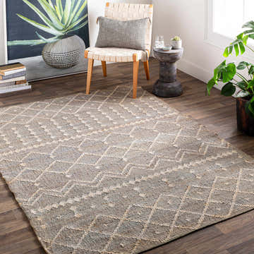 Bohemian living room with Armidale Hand Woven Beige Jute Rug, woven chair, and potted plant. Roomscene-Rectangle