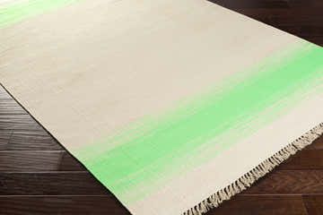 Close-up of the hand woven Arock Area Carpet. Light beige rug with a green stripe and fringed edge. Corner