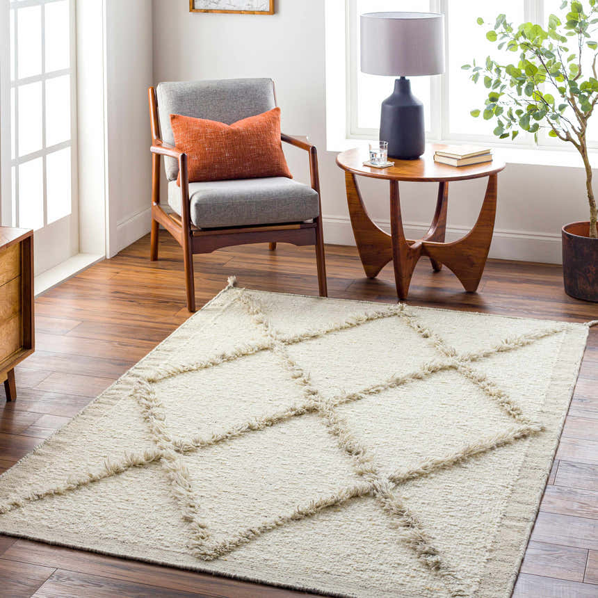 Living room scene with a beige Awen Hand Knotted Wool Area Rug, gray chair, wood furniture, and warm, inviting light. Roomscene-Rectangle