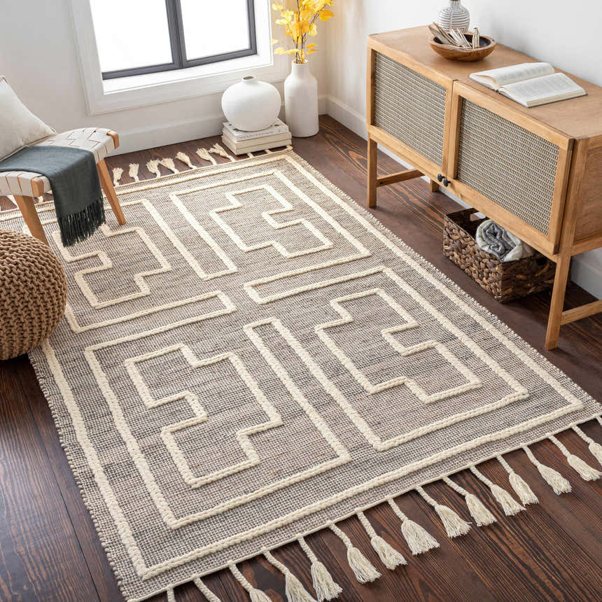 Living room scene with a charcoal and cream Azra Tasseled Jute & Wool Rug, wood floors, and a woven accent chair. Roomscene-Rectangle