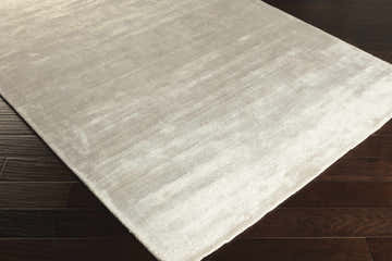 Close-up of the white Barree Area Carpet showing its contemporary design and soft, viscose texture on dark wood flooring. Corner