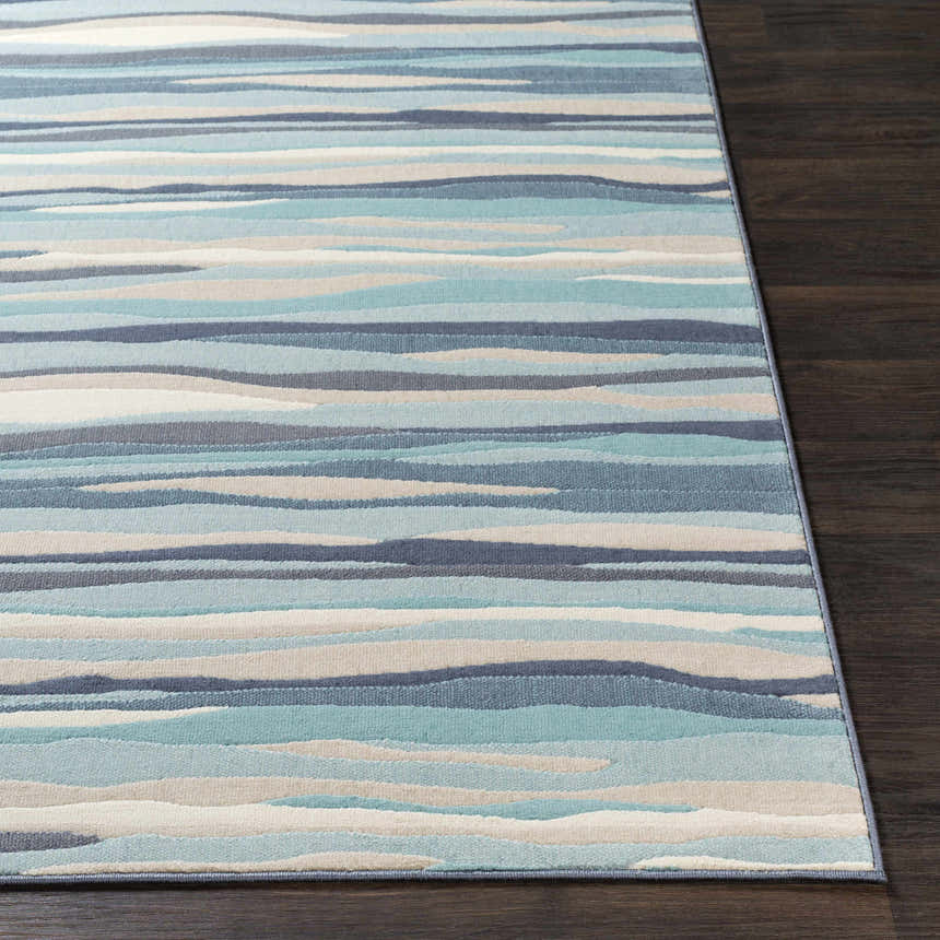 Close-up of the Basco Area Rug, featuring horizontal stripes in aqua, charcoal, light beige, and blue on dark wood flooring. Front