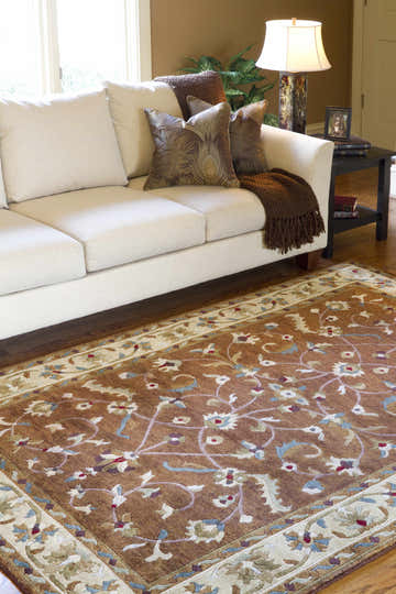 Living room scene with a beige sofa and the brown floral Batesburg Wool Area Carpet. Roomscene-Rectangle