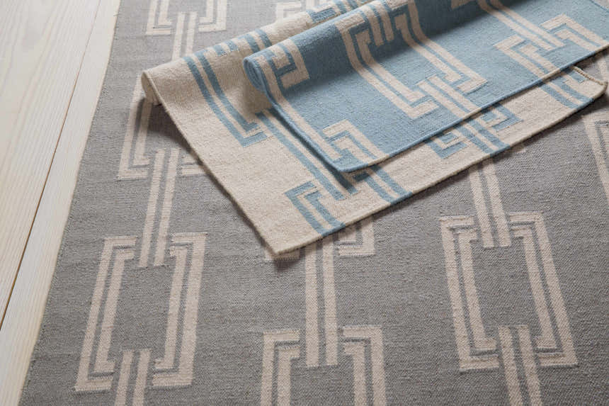 Close-up of the Billerica Area Carpet, a hand-woven wool rug with a beige and dusty sage geometric pattern. Styleshot