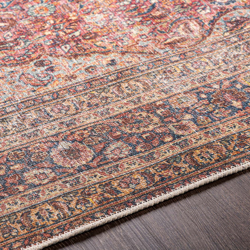 Close-up of the Belison Washable Area Rug. Traditional, farmhouse style with red, orange, and blue tones. Machine woven texture. Texture